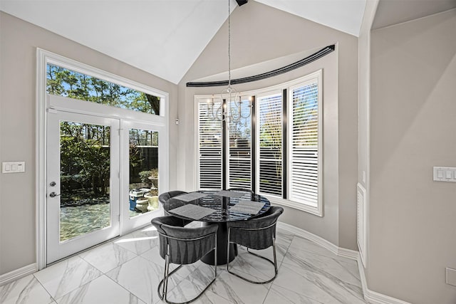 dining room with a wealth of natural light, lofted ceiling, a notable chandelier, and marble finish floor