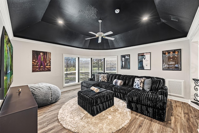 living room featuring visible vents, wood finished floors, a raised ceiling, and ornamental molding