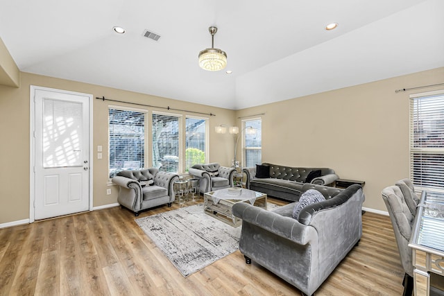 living area with visible vents, baseboards, wood finished floors, and vaulted ceiling