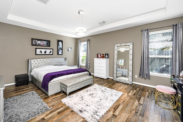 bedroom with a raised ceiling, baseboards, and wood finished floors