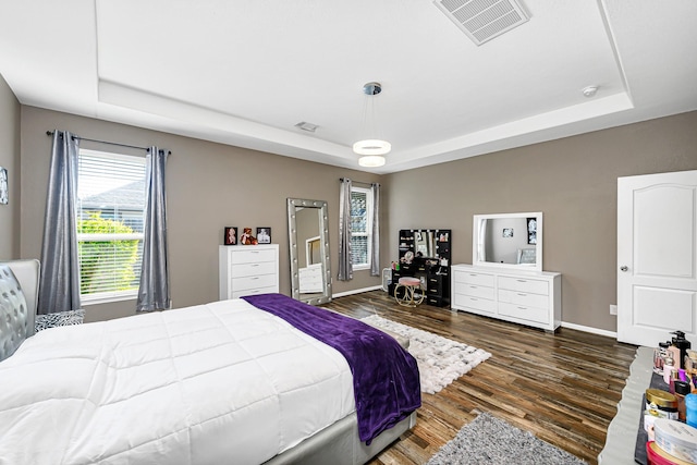 bedroom featuring visible vents, a raised ceiling, and wood finished floors