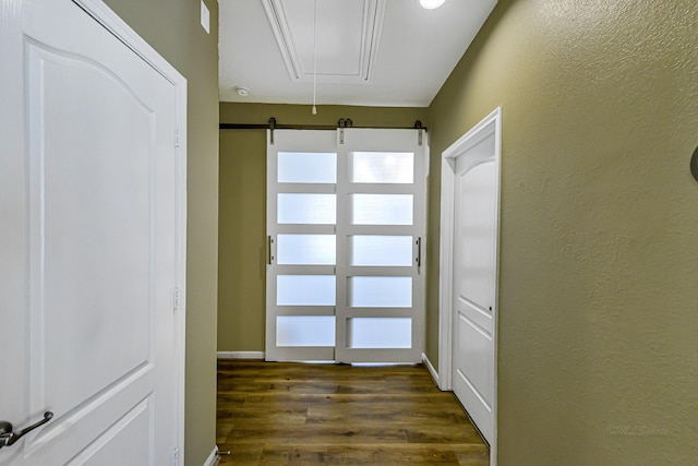 doorway featuring dark wood finished floors, a barn door, and a textured wall