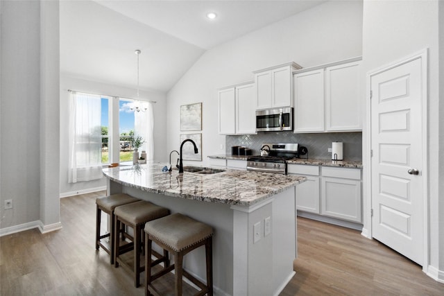 kitchen featuring a center island with sink, a sink, tasteful backsplash, appliances with stainless steel finishes, and white cabinets