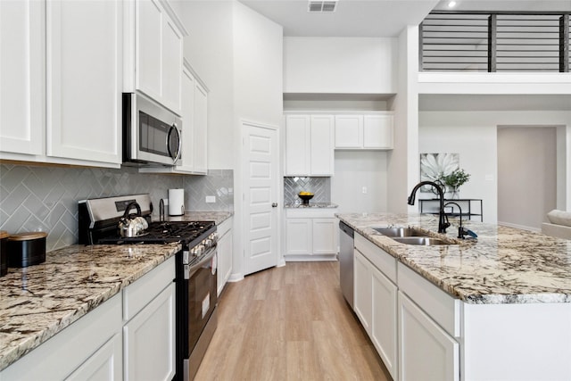 kitchen featuring a sink, stainless steel appliances, light wood-type flooring, and white cabinets