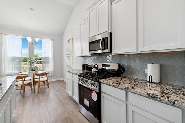 kitchen with lofted ceiling, stainless steel appliances, white cabinets, light wood-type flooring, and backsplash