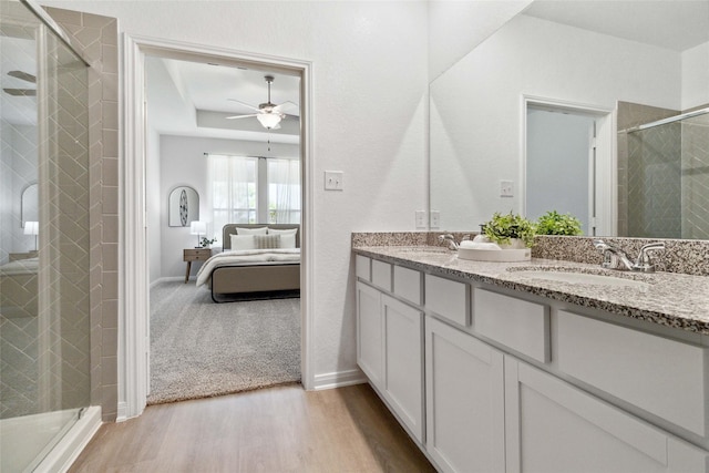 bathroom with wood finished floors, ensuite bath, double vanity, a sink, and a shower stall