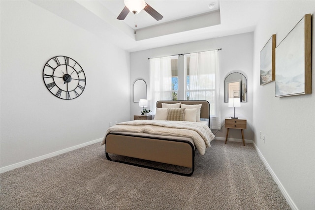 bedroom with a raised ceiling, carpet flooring, a ceiling fan, and baseboards