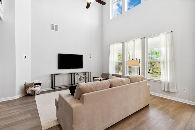 living room featuring visible vents, baseboards, a ceiling fan, and light wood finished floors