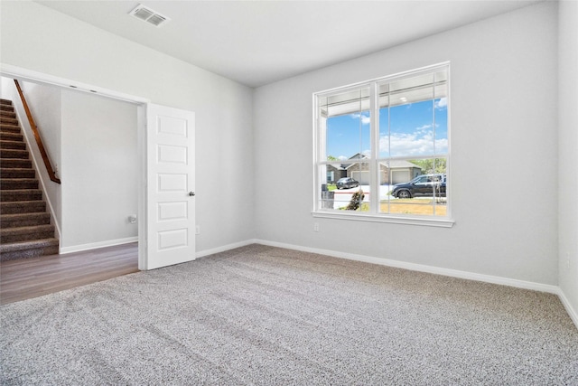 unfurnished room featuring stairway, carpet, visible vents, and baseboards