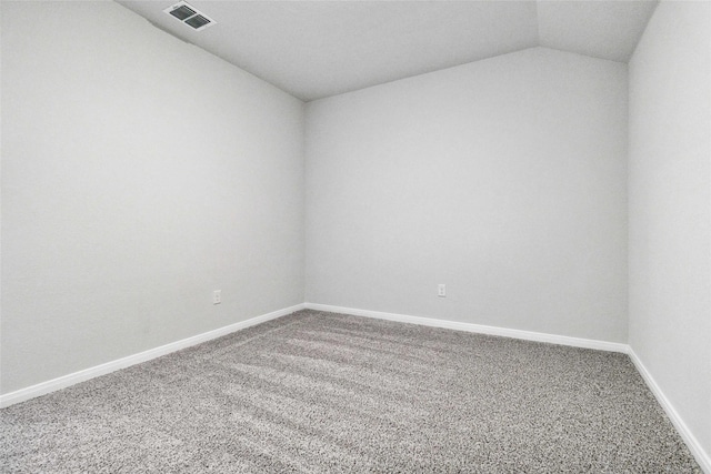 carpeted empty room featuring visible vents, baseboards, and vaulted ceiling