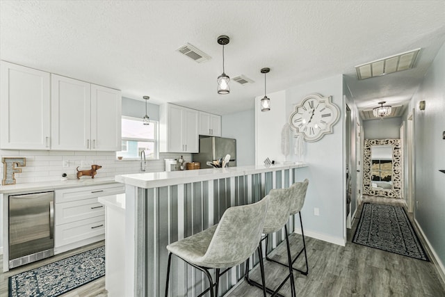 16715 Montego Way, Jamaica Beach, TX 77554 - kitchen with visible vents, wood finished floors, freestanding refrigerator, and beverage cooler