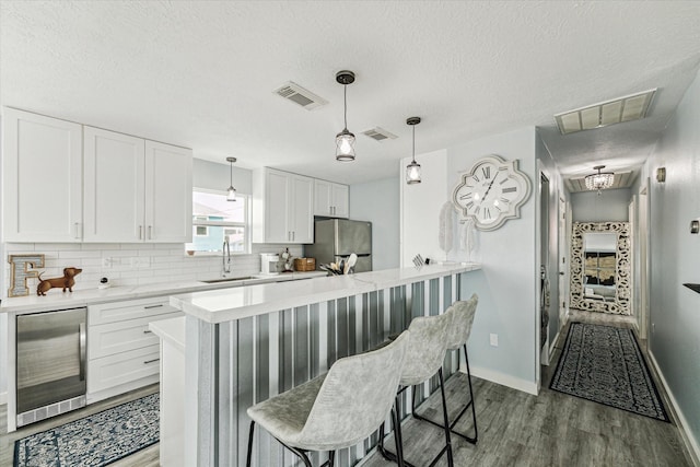 kitchen with wine cooler, a breakfast bar area, visible vents, and a sink