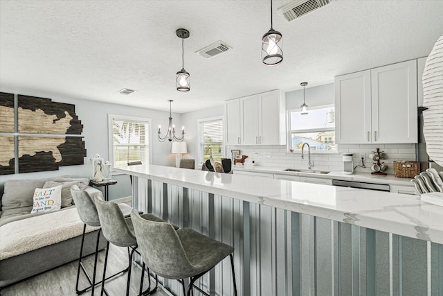 kitchen featuring decorative backsplash, open floor plan, visible vents, and a sink