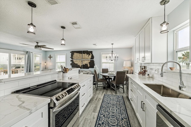 kitchen with visible vents, decorative backsplash, light wood-style flooring, stainless steel appliances, and a sink