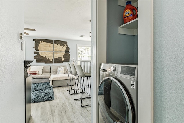 clothes washing area featuring laundry area, washer / dryer, a textured wall, and wood finished floors