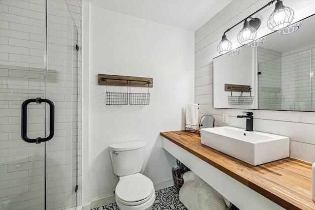 full bathroom featuring a sink, baseboards, toilet, and a shower stall