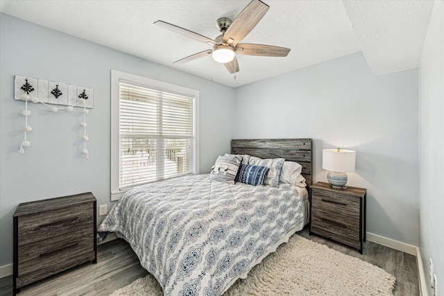 bedroom featuring baseboards, a textured ceiling, wood finished floors, and a ceiling fan