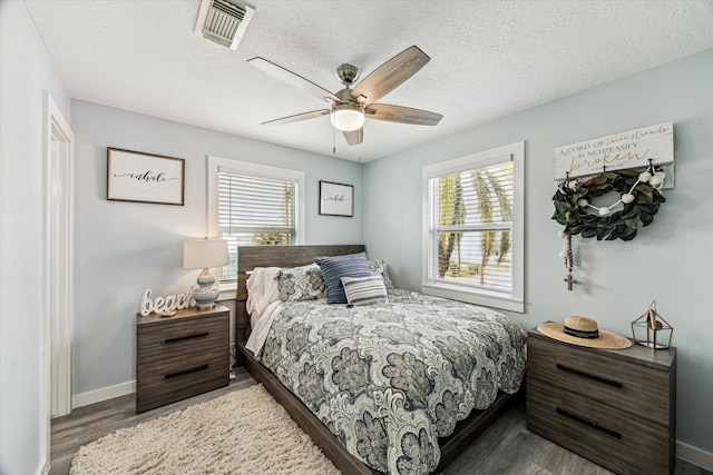 bedroom featuring multiple windows, wood finished floors, visible vents, and a textured ceiling