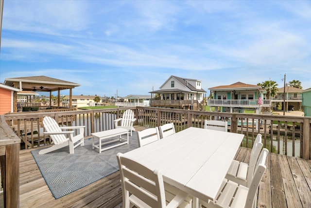 wooden terrace with a residential view, outdoor dining space, and a water view