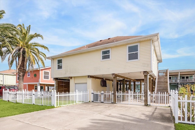 back of property featuring a fenced front yard, a carport, driveway, and a gate