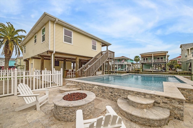 view of pool with a deck, a patio, fence, a fire pit, and stairs