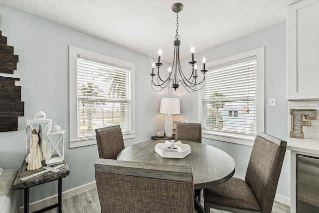 dining space with wine cooler, a textured ceiling, baseboards, and wood finished floors