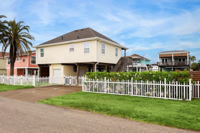 16715 Montego Way, Jamaica Beach, TX 77554 - view of front of property featuring a front lawn, a fenced front yard, concrete driveway, a garage, and stairway