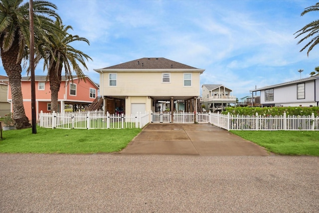 16715 Montego Way, Jamaica Beach, TX 77554 - coastal inspired home with fence private yard, an attached garage, a front lawn, and concrete driveway
