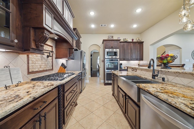 kitchen with visible vents, stainless steel appliances, arched walkways, light tile patterned flooring, and light stone countertops