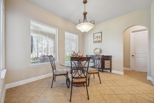 dining room with light tile patterned floors, baseboards, and arched walkways