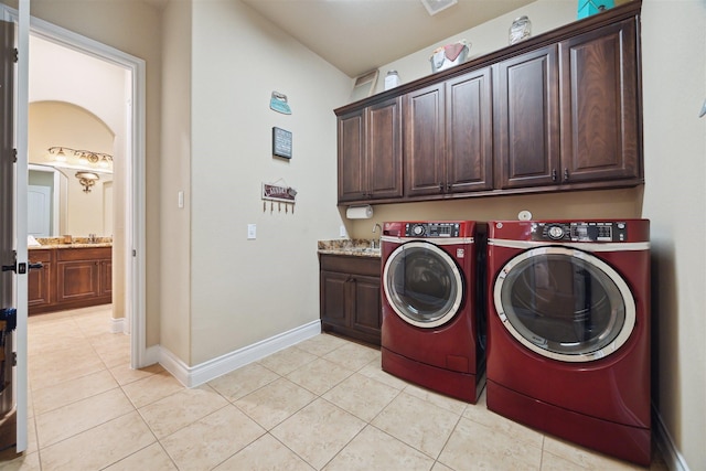 laundry room featuring baseboards, washing machine and clothes dryer, light tile patterned flooring, cabinet space, and a sink