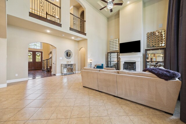 living room with light tile patterned floors, baseboards, arched walkways, and a fireplace