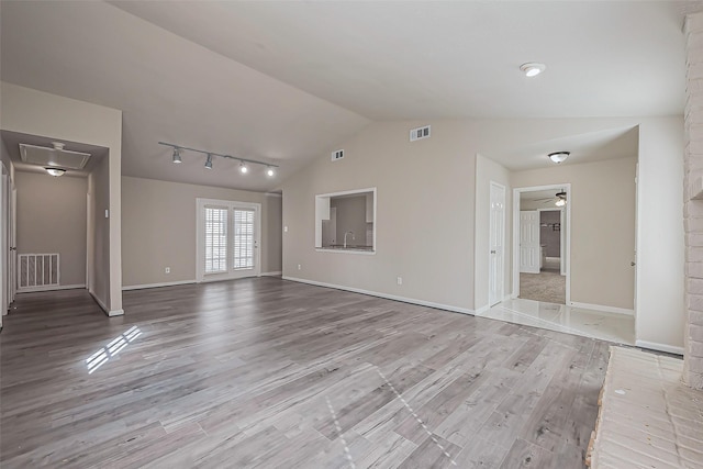 unfurnished living room featuring visible vents, wood finished floors, and vaulted ceiling