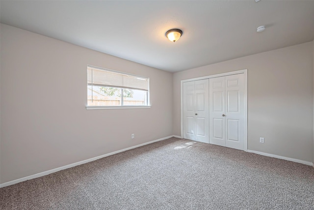 unfurnished bedroom featuring carpet flooring, baseboards, and a closet