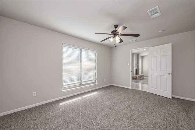 carpeted empty room with a ceiling fan, visible vents, and baseboards