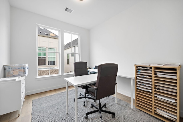 home office featuring visible vents, light wood-type flooring, and baseboards