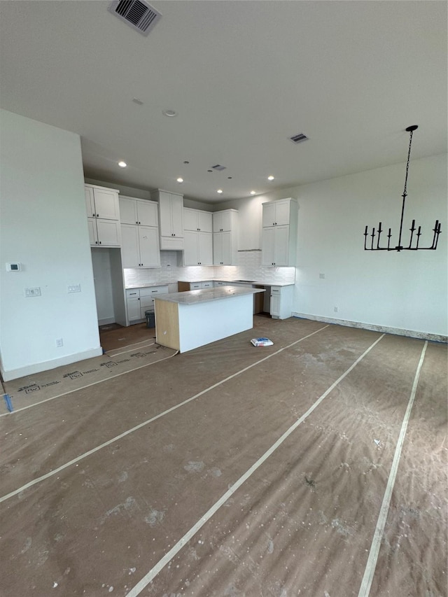 kitchen with white cabinets, visible vents, backsplash, and a kitchen island