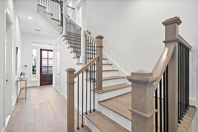 stairs with hardwood / wood-style floors, visible vents, baseboards, a high ceiling, and recessed lighting