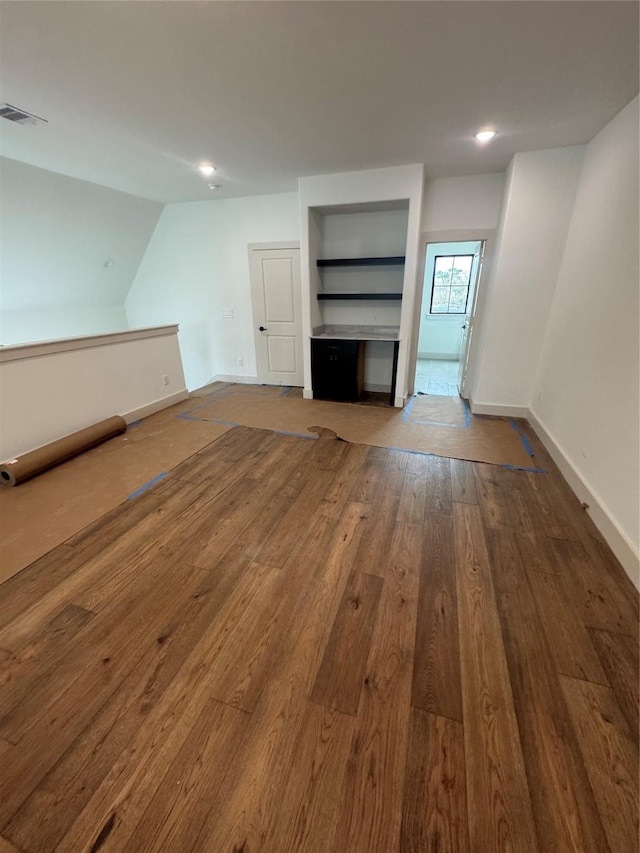 unfurnished living room with visible vents, baseboards, and hardwood / wood-style floors