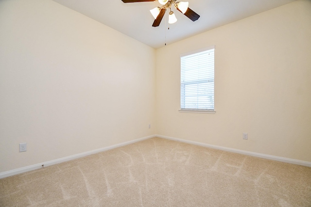 spare room featuring a ceiling fan, vaulted ceiling, light colored carpet, and baseboards