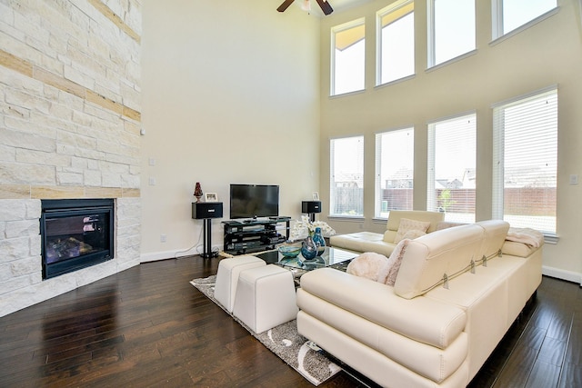 living room featuring a stone fireplace, dark wood-style floors, and a healthy amount of sunlight