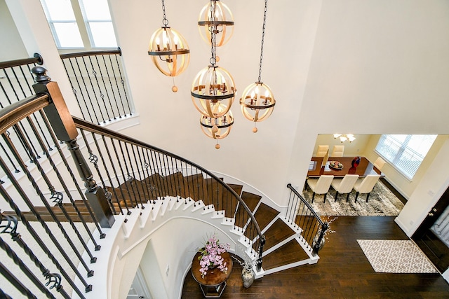 stairway with a chandelier, plenty of natural light, and a high ceiling