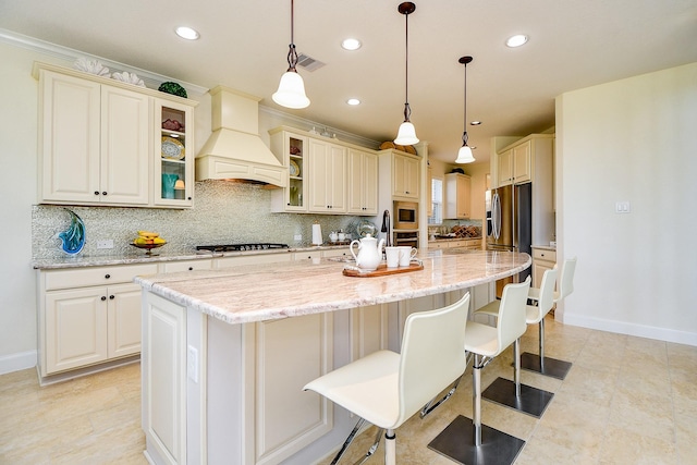 kitchen featuring backsplash, a kitchen bar, an island with sink, custom range hood, and appliances with stainless steel finishes