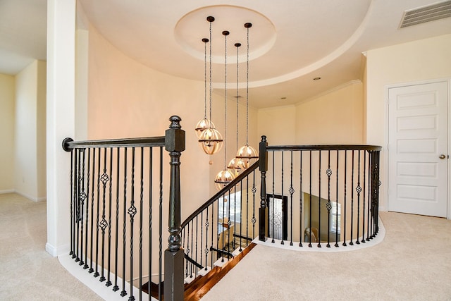 stairway with baseboards, visible vents, carpet floors, a raised ceiling, and a chandelier