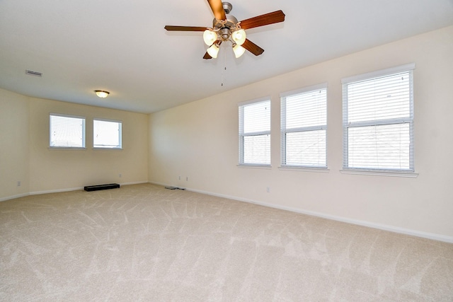 spare room featuring visible vents, light colored carpet, and baseboards