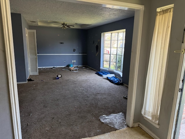 spare room featuring ceiling fan, baseboards, and a textured ceiling