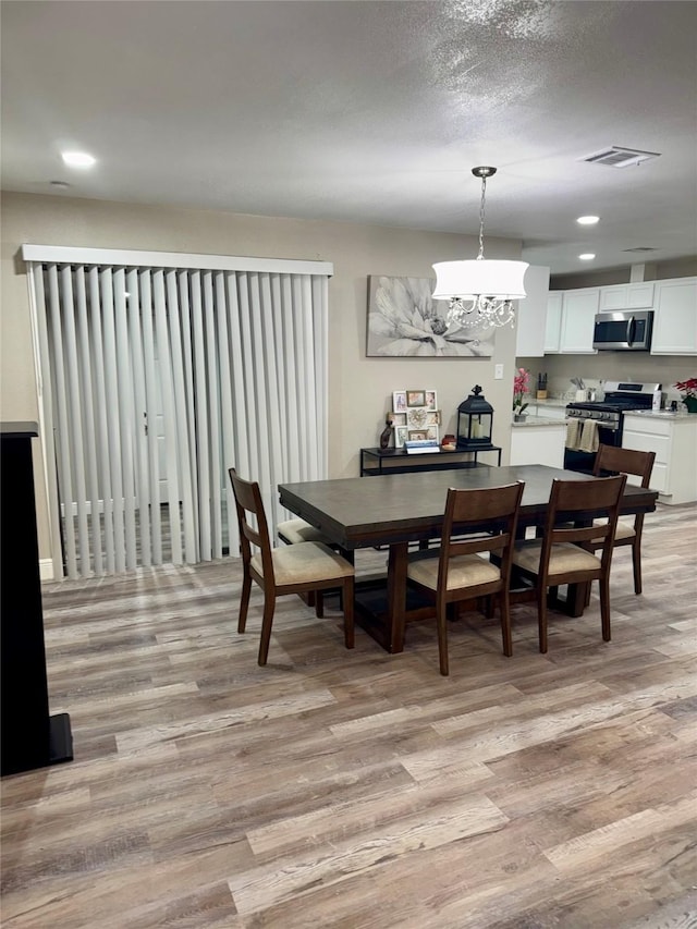 806 Moody Ave, League City, TX 77573 - dining room with visible vents, a textured ceiling, an inviting chandelier, and light wood finished floors