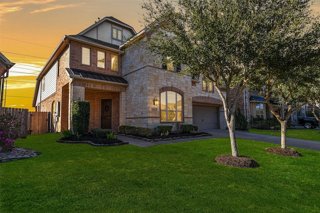 view of front facade featuring fence, aphalt driveway, a garage, a yard, and a standing seam roof