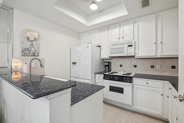 kitchen with visible vents, a tray ceiling, white cabinetry, white appliances, and a peninsula