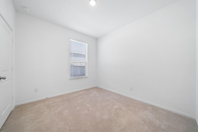 spare room with light carpet and baseboards